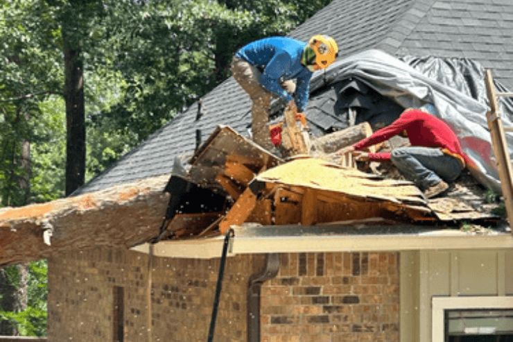 Amaya Tree Service crew cutting a fallen tree off a storm-damaged roof near Huntsville, TX
